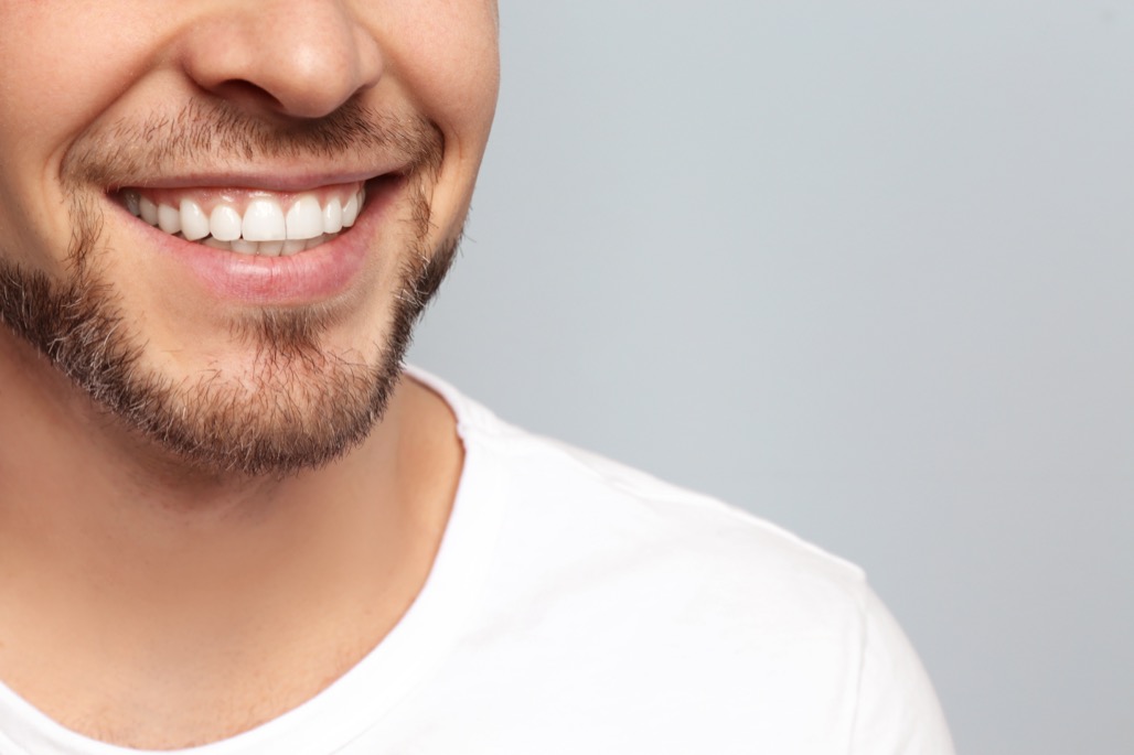 Young,Man,With,Beautiful,Smile,On,Grey,Background.,Teeth,Whitening