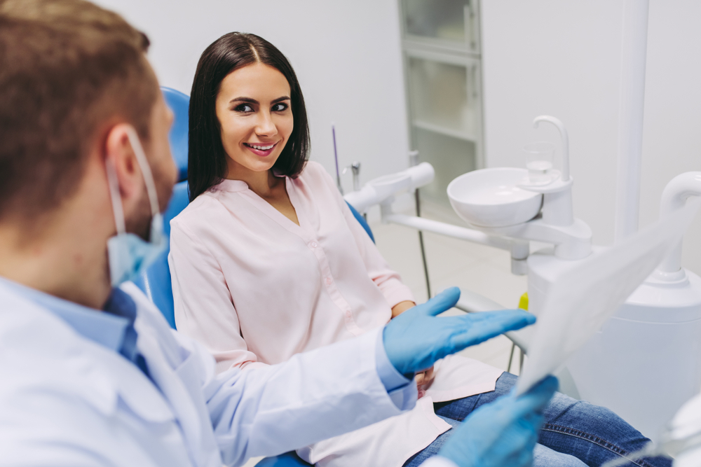 Young,Patient,Talking,With,Dentist,Looking,At,X-ray,In,Modern